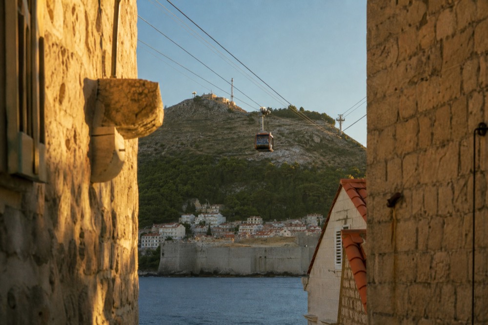 The Dubrovnik cable car cabin ascending the cableway above the Old Town toward Mount Srd at golden hour