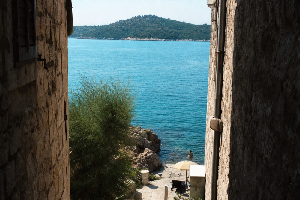Calm turquoise water along a rocky shore with a distant island