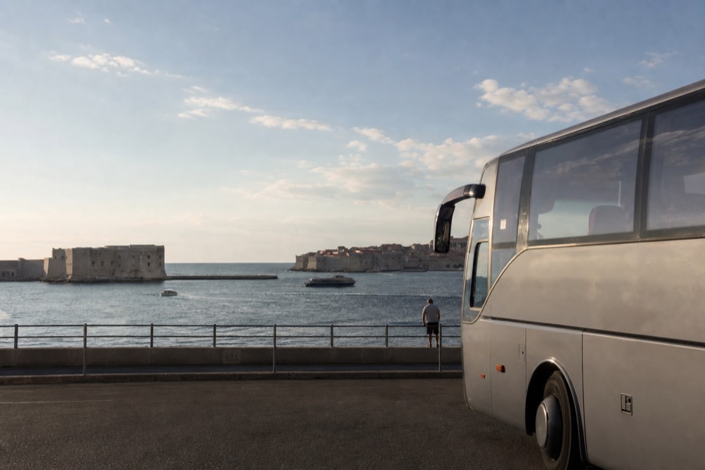 A long-distance bus parked at a coastal station above the Adriatic