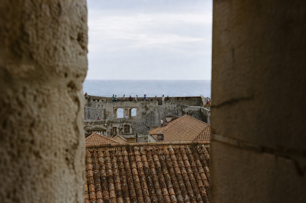 Walkers on the high city walls of Dubrovnik above red rooftops