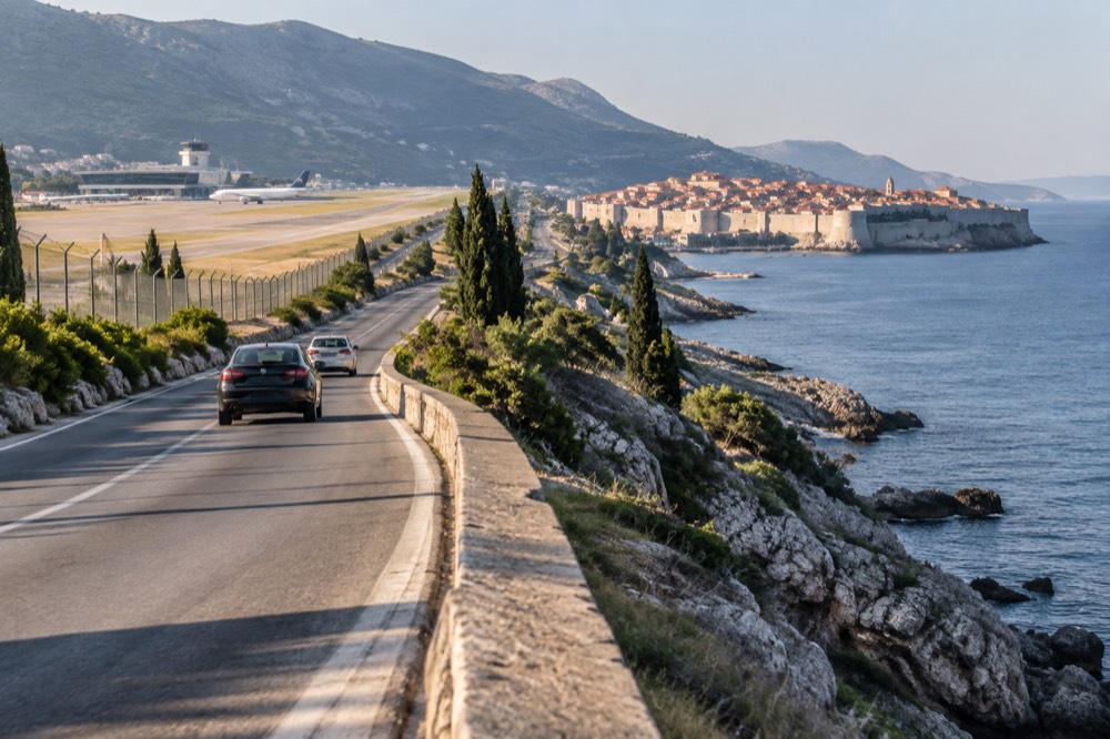 A coastal road winding between the airport and the walled city with the sea on one side