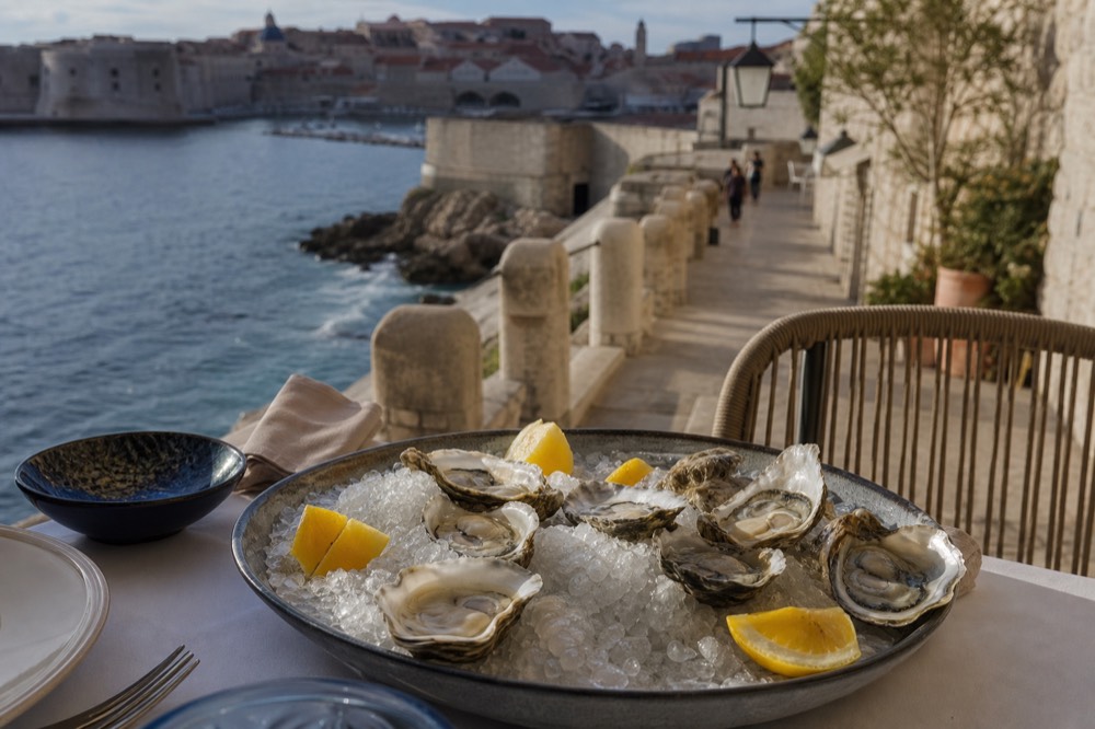 Fresh oysters on ice with lemon wedges on a restaurant table by the sea