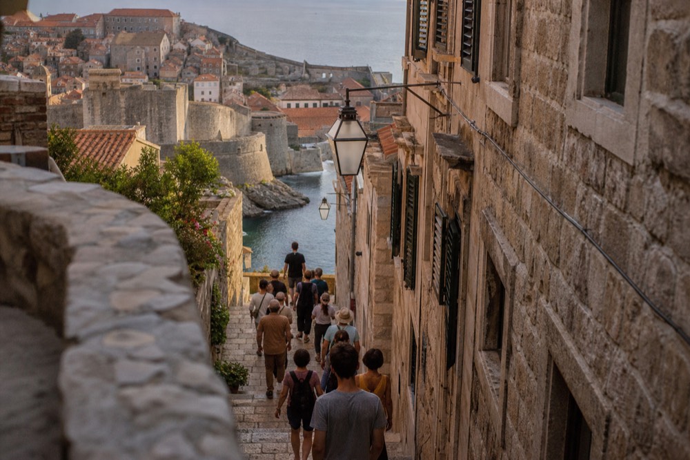 A guide leading a small group through a narrow stone street with tasting stops