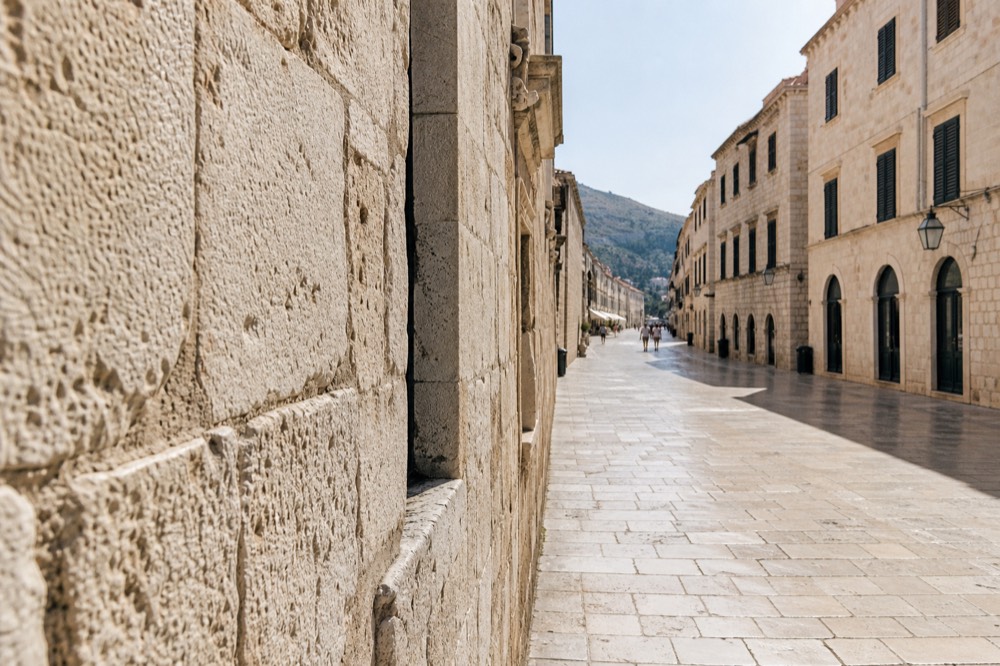 Empty early morning limestone street in Dubrovnik Old Town with shutters closed and soft light