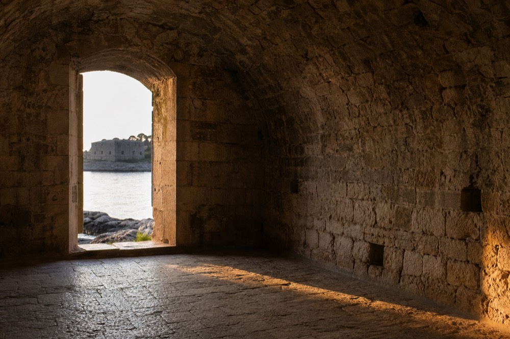 An empty vaulted stone chamber on Lokrum island, bare walls and a worn stone floor
