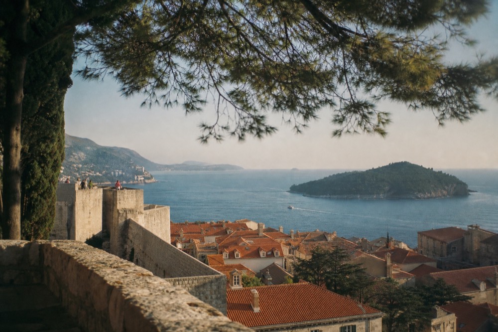 Sunlit stone ramparts above red rooftops seen from a high vantage point