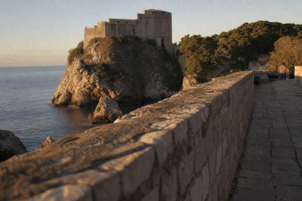 A stone fortress on a rocky promontory above calm blue sea