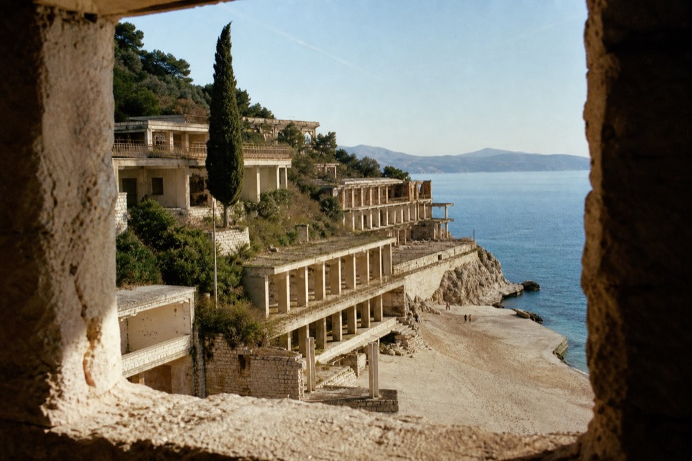 Roofless abandoned hotel buildings standing above an empty beach near Dubrovnik