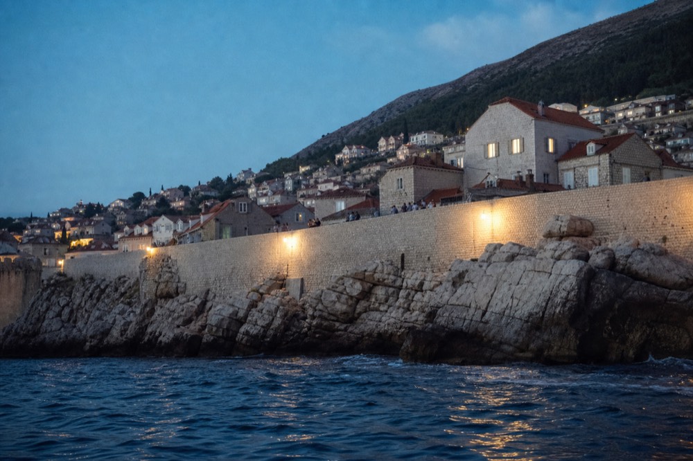 Walkers on the Dubrovnik city walls above red rooftops
