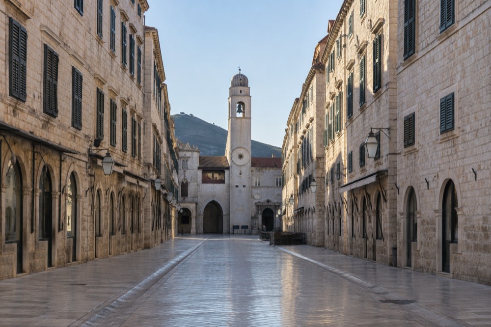 The Stradun in Dubrovnik empty in early morning light with the clock tower ahead