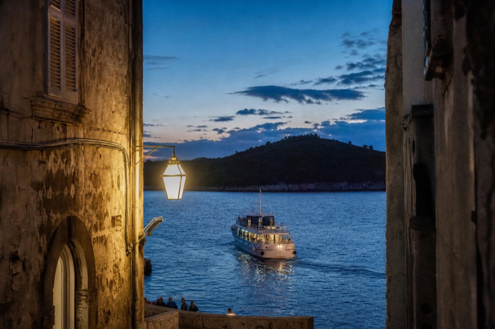 A passenger boat approaching a wooded island from the old harbour of Dubrovnik