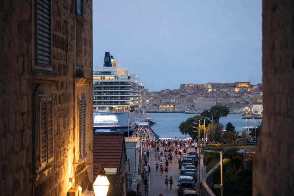 A cruise ship docked in the Gruž port with the Old Town in the distance, showing the scale of the crowds