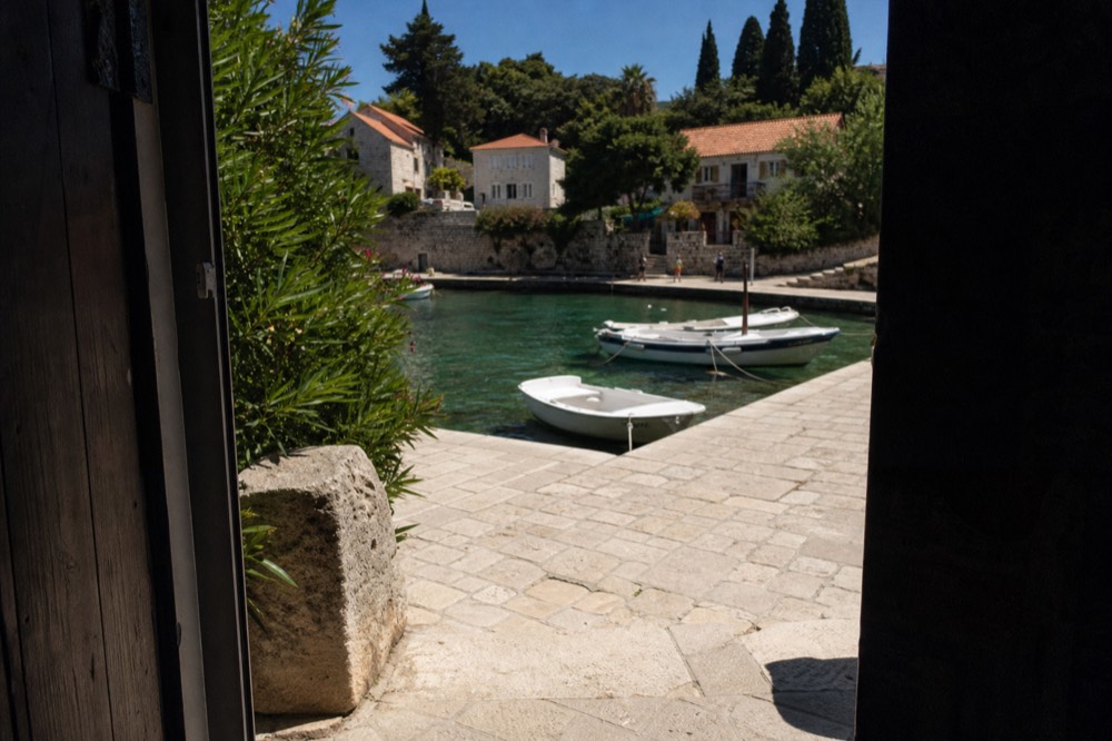 A stone harbour village with small boats moored in clear green water