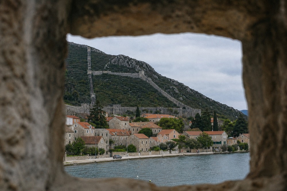 Long stone walls of Ston climbing a dry hillside above red rooftops