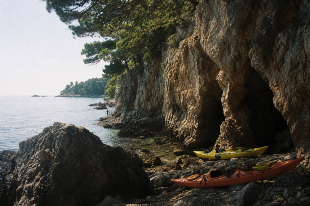 Kayaks pulled onto rocks near a sea cave entrance