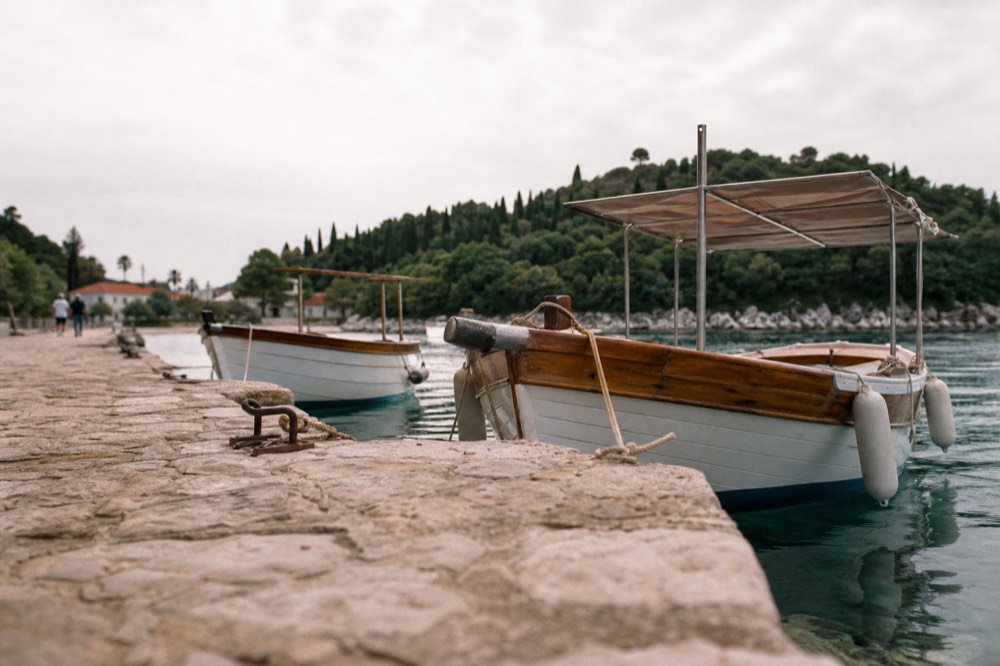 A stone quay in a small island bay with wooden boats moored in clear water
