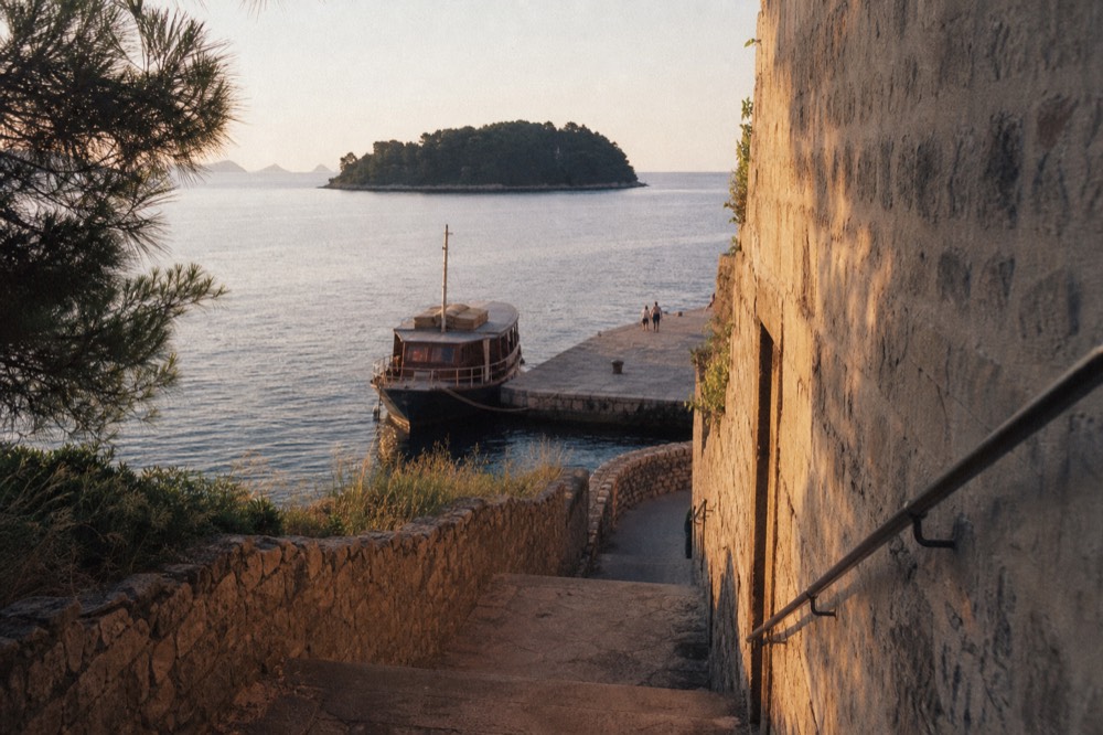 A wooden tourist boat moored at a small island jetty in morning light