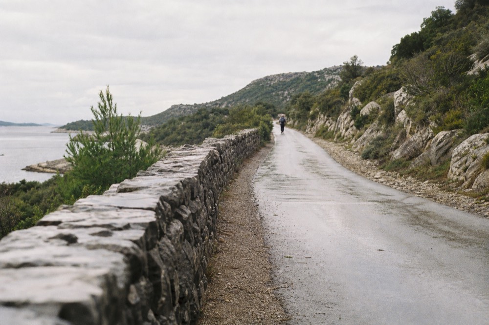 A quiet country road winding through dry rocky hills with scattered shrubs