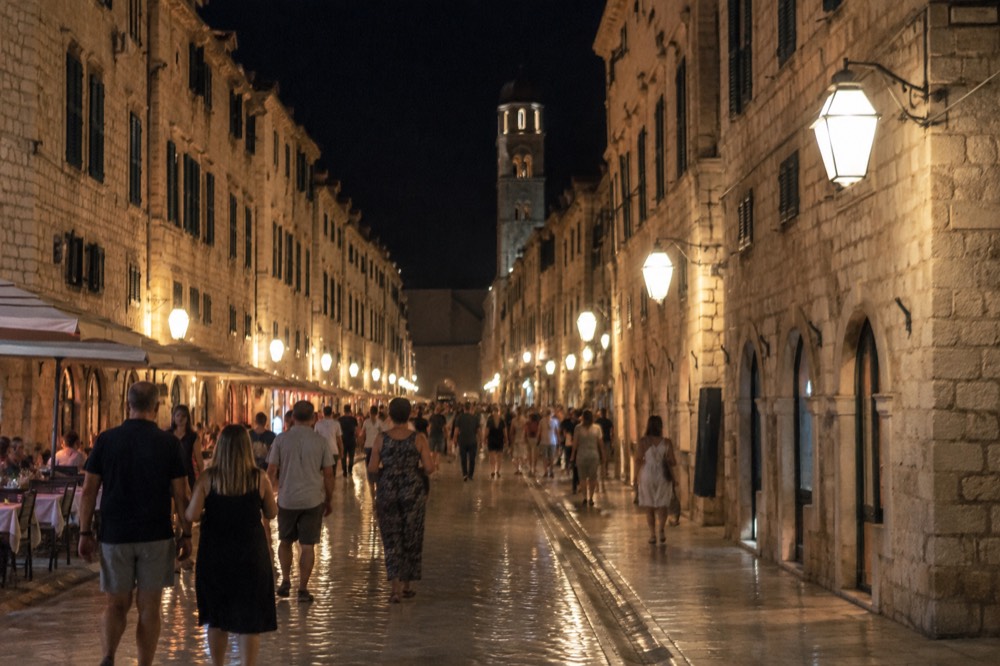 The Stradun in Dubrovnik at night with lamplit stone buildings and people strolling