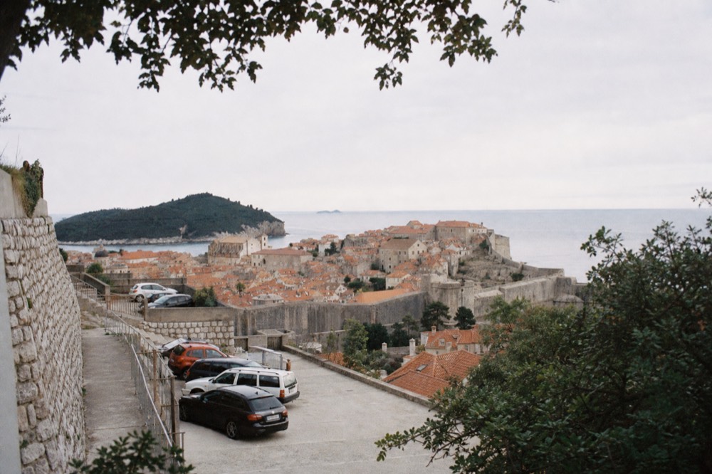 Cars parked in a terraced garage above red rooftops and the sea