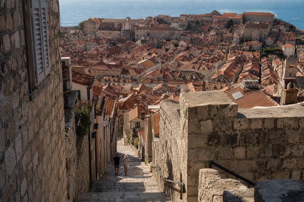 The walled city of Dubrovnik seen from a hillside above terracotta roofs