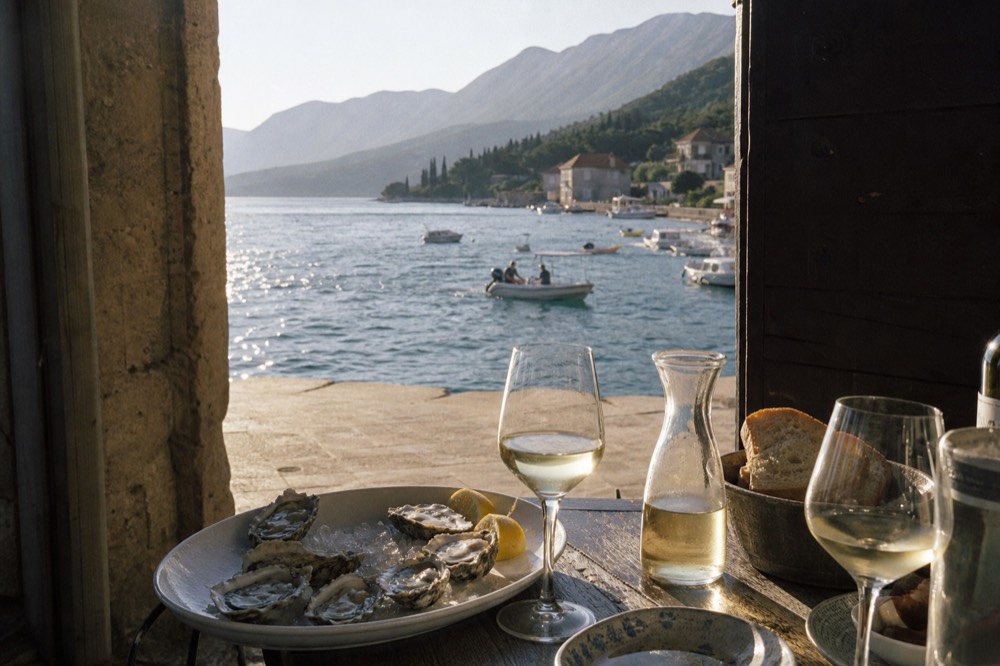 Fresh oysters on a platter beside glasses of white wine