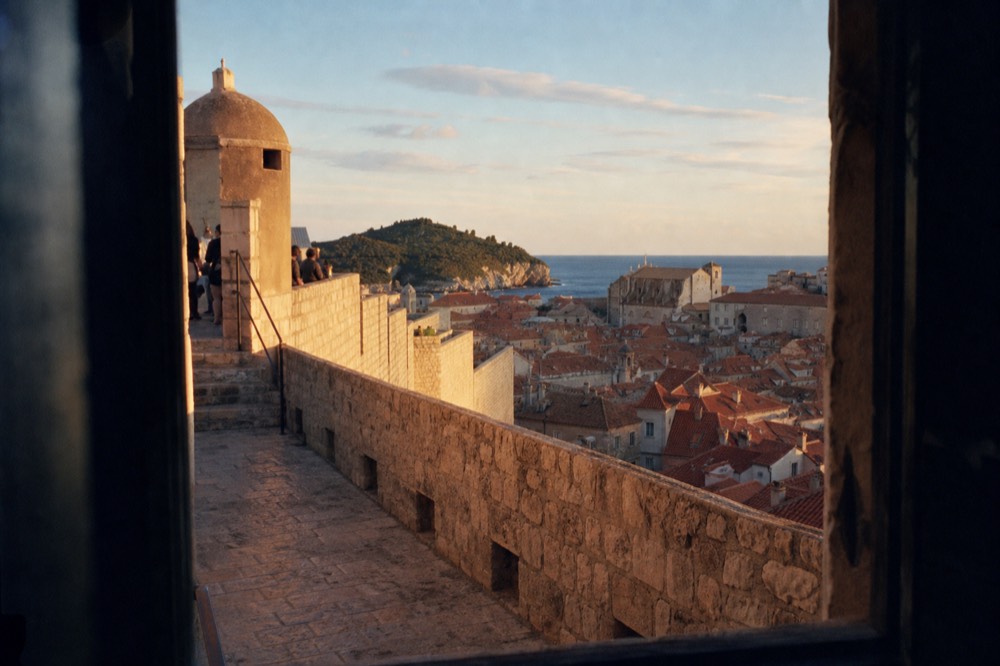 Evening view over terracotta rooftops with the illuminated old city walls in the foreground