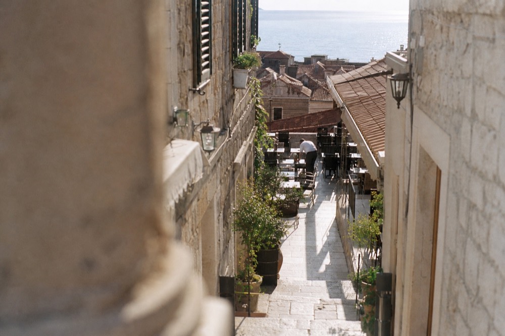 Waiter setting tables on an empty restaurant terrace before evening service