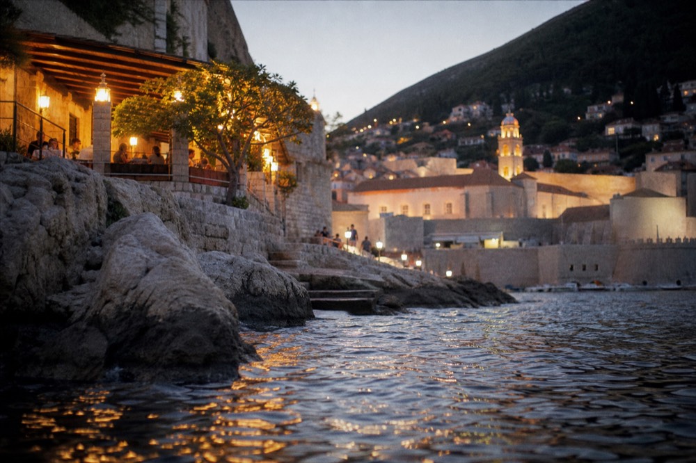 Evening restaurant terrace glowing under lanterns with the illuminated city behind