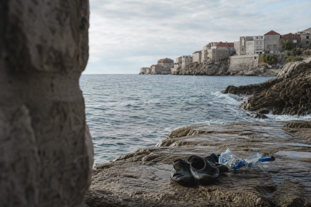 A pair of snorkel masks and water shoes resting on a coastal rock ledge