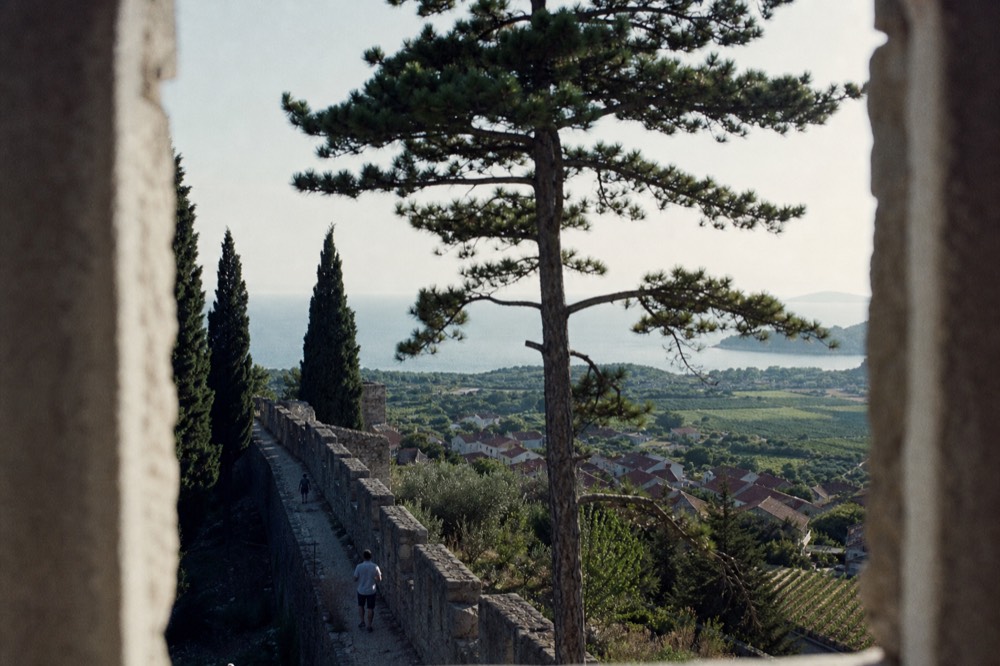 A long stone wall following the crest of a hill above rooftops and green fields