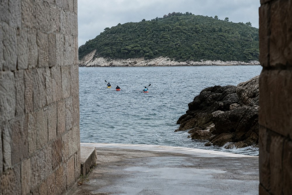 Sea kayaks paddling along rocky coastline toward Lokrum island
