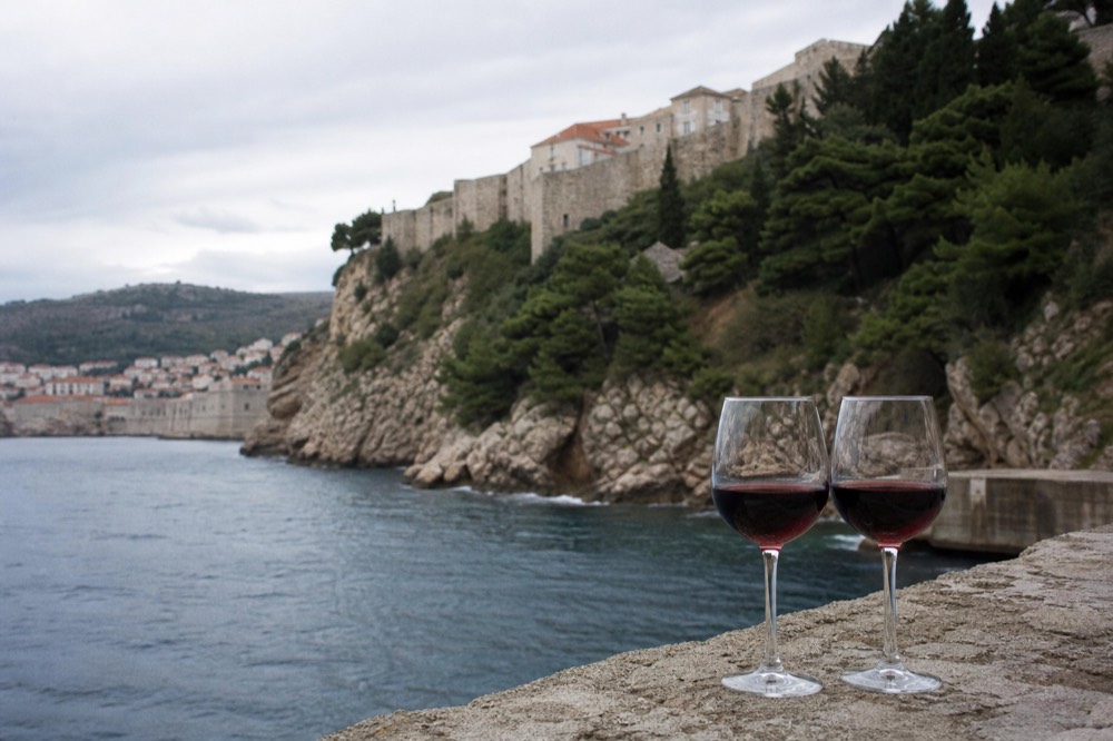 Glasses of red wine on a stone terrace overlooking the Adriatic coast