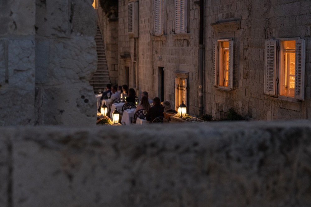 Cafe terrace with white tablecloths along a stone lane in Dubrovnik Old Town