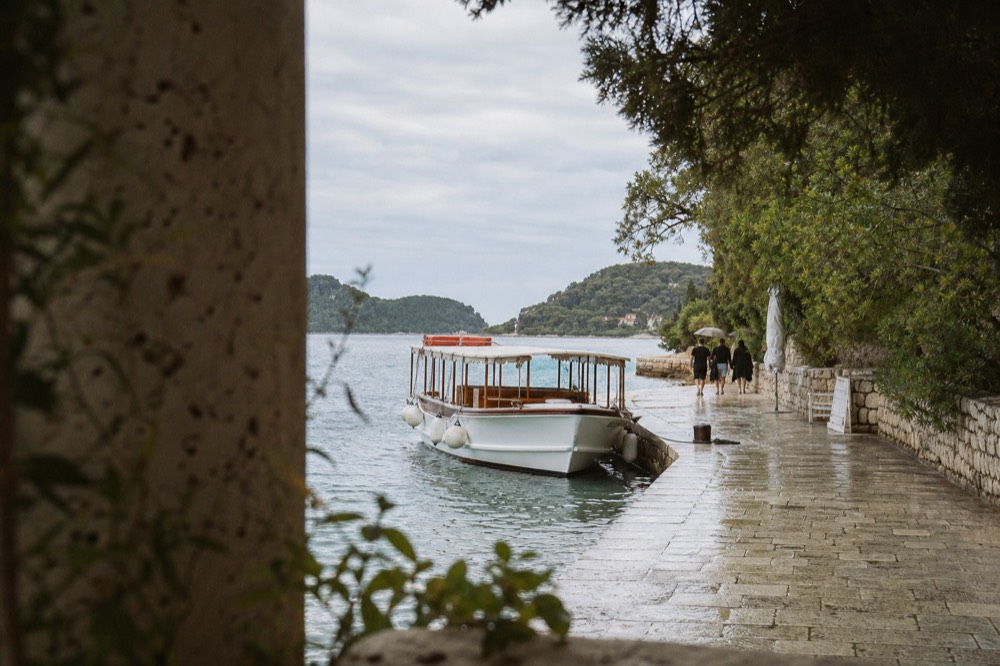 A small passenger boat moored at a stone quay beside a waterfront promenade