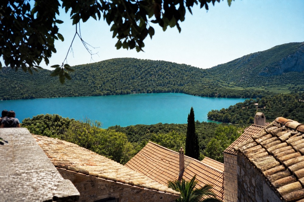 A turquoise lake surrounded by dense green forest under a clear sky