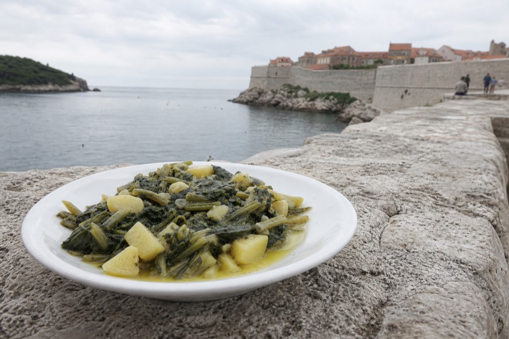 A plate of traditional blitva, a Croatian side dish of Swiss chard, potatoes, and garlic, served with olive oil.