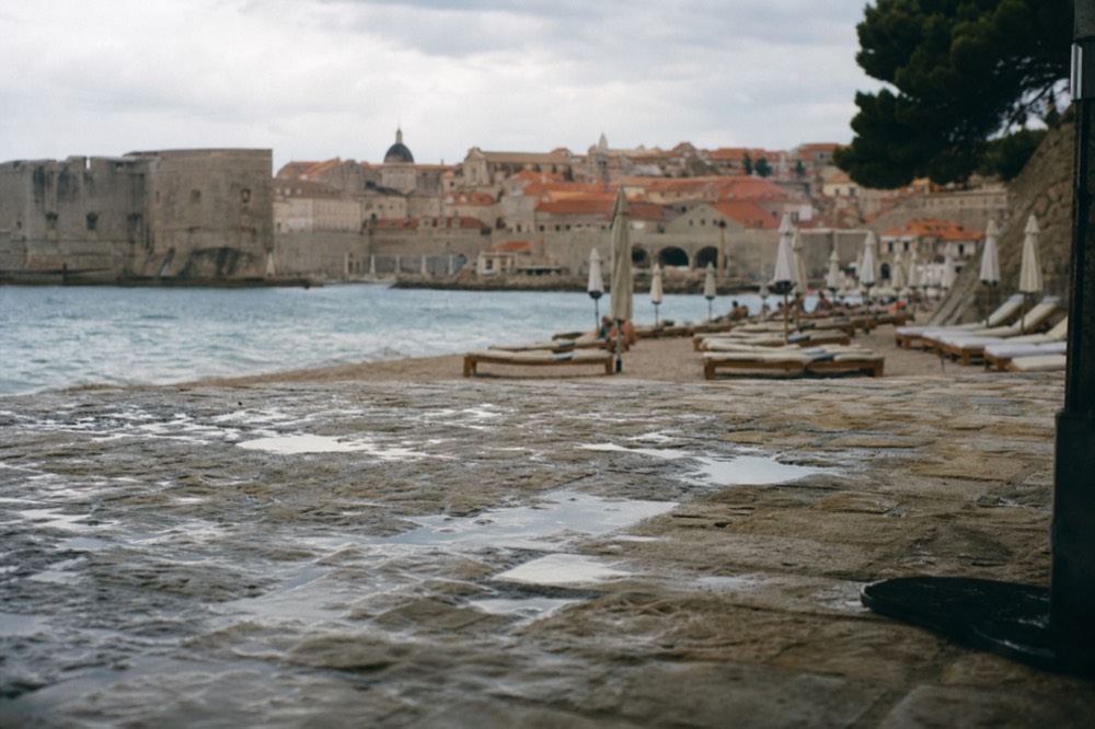 A view of Banje Beach with sunbeds and the Old Town in the background.