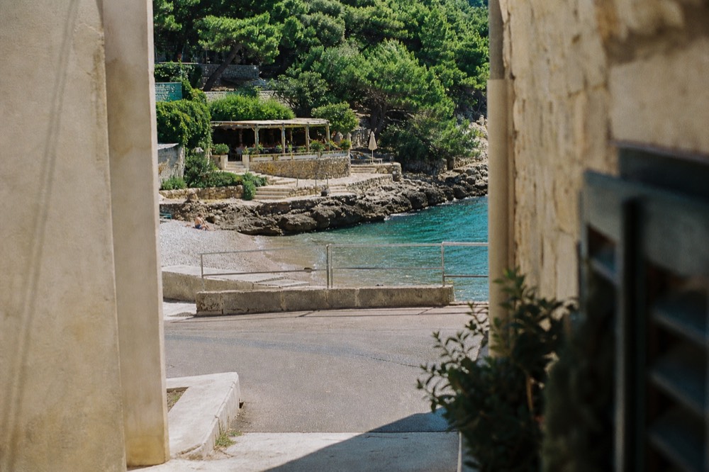 A quiet cove on Lapad peninsula with a small beach bar and lush green vegetation.