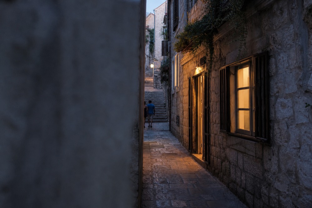 A narrow limestone lane in Dubrovnik Old Town leading toward a stone staircase