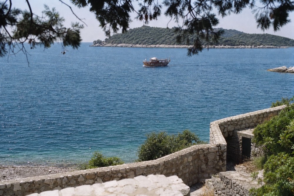 A wooden boat approaching a green island in the Elaphiti archipelago