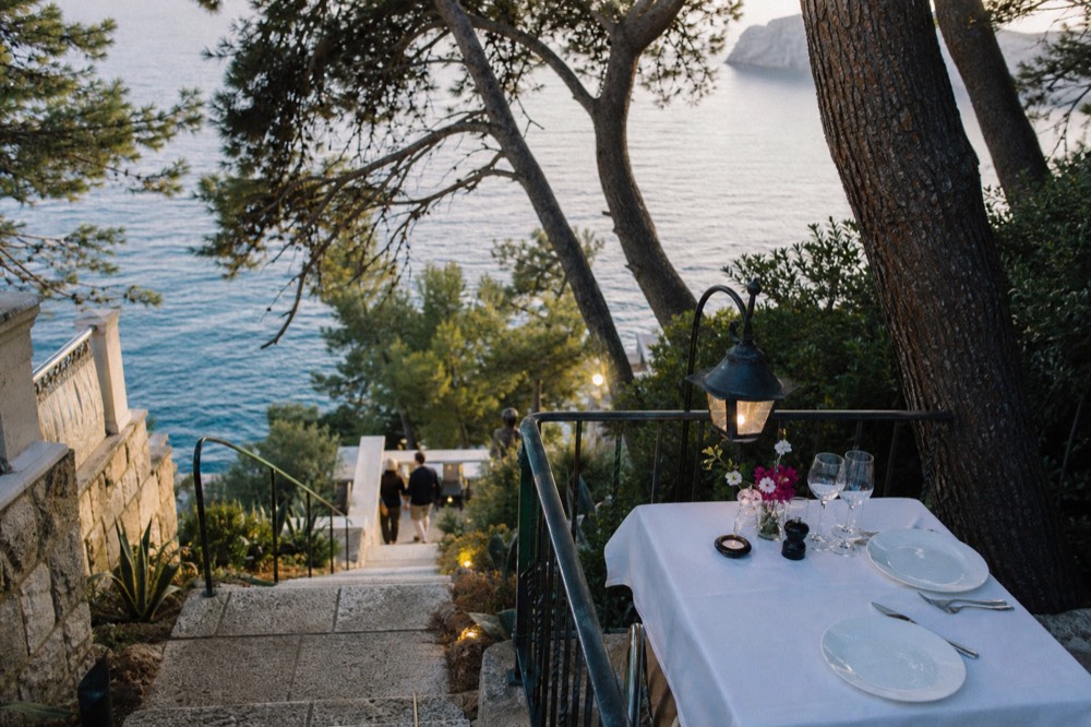 A restaurant terrace table set for dinner above the Adriatic at dusk