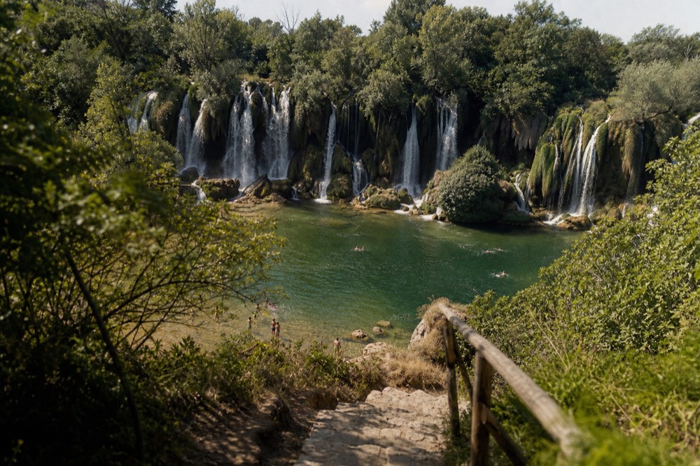 Kravica waterfall in Bosnia falling into a green pool surrounded by cliffs