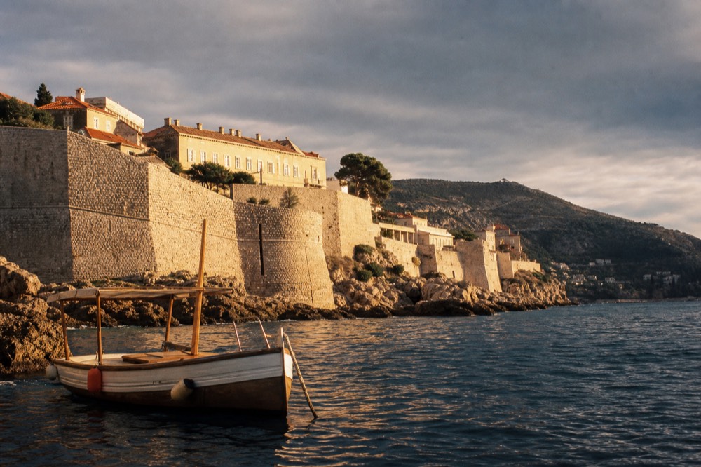 Wooden boat moored in a sheltered Adriatic cove under grey clouds