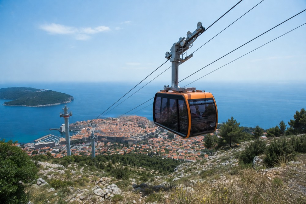 The Dubrovnik cable car cabin ascending toward Mount Srd above the Old Town rooftops